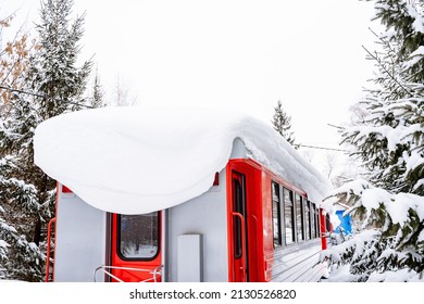 A Red Wagon Stands Under A Layer Of Snow At The Station. A Snowdrift Hangs On The Roof. High Quality Photo