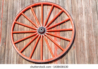 Red Wagon Wheel On A Barnwood Building