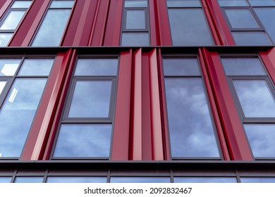 Red wall with many windows. Bottom view of a red building with many windows