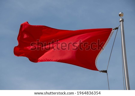 Red warning flag at the beach Red fabric cloth in blue sky. Wavy background Communist, Communism, Rebellion, Revolution