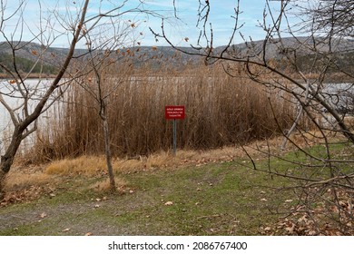 Red warning sign by the lake:  "It is dangerous and forbidden to enter the lake" (Göle girmek tehlikeli ve yasaktir in Turkish) - Shutterstock ID 2086767400