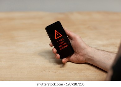 Red Warning Text Saying ‘I Have Your Private Pictures’ On A Hacked Cell Phone. The Hand Of He Sextortion Victim Holding His Phone While Being Desperate. Cybercrime, Ransomware