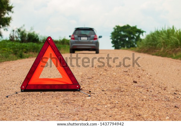 Red warning triangle. Focus on red triangle!,\
beside rural road.