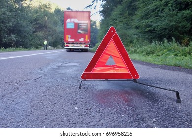 Red Warning Triangle On A Road With A Broken Down Truck.