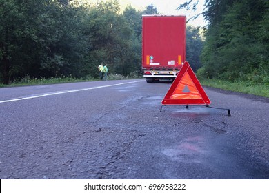 Red Warning Triangle On A Road With A Broken Down Truck.