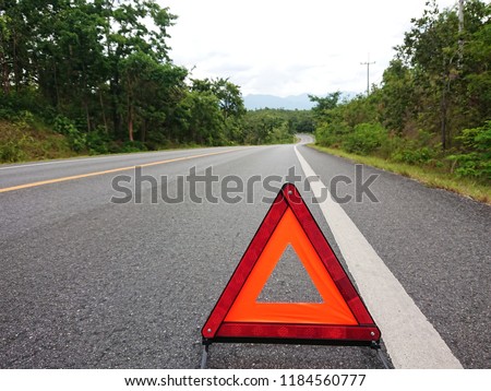 Red warning triangle on the road sign with cloudy day