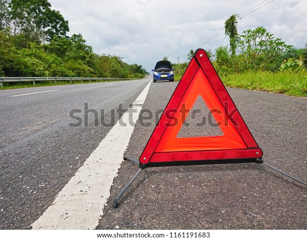 Red\
warning triangle on the road sign with a broken\
car.