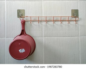 A Red Water Ladle Is Hung On A Hanger In A Bathroom