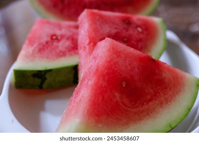 Red watermelon cut into triangles, on a white plate, stock photo.