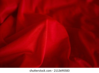 Red waves of fabric background. Elegant blood color soft silky drapery. Romantic passionate tint of bedsheets.