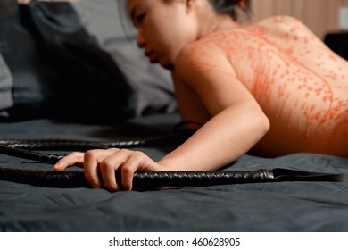 Red wax on skin of young submissive woman on a bed