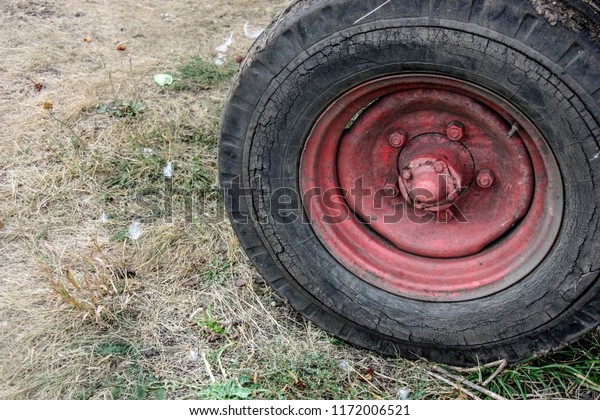 Red wheel of an old tractor on the village\
ground. Autumn harvest time. Front\
view