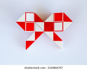 red and white bicolor magic snake Transformable twist puzzle in shape of bow isolated on white background. it develops spatial thinking. version 1