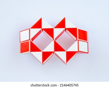 red and white bicolor magic snake Transformable twist puzzle in shape of carnival mask or glasses isolated on white background. it develops spatial thinking.