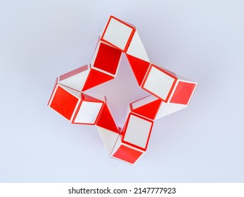 red and white bicolor magic snake Transformable twist puzzle in shape of ninja star isolated on white background. it develops spatial thinking.