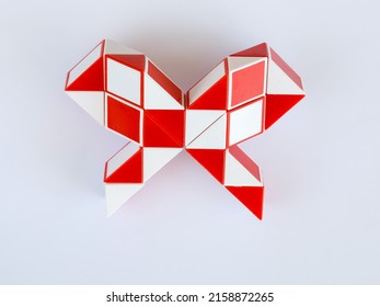 red and white bicolor magic snake Transformable twist puzzle in shape of bow isolated on white background. it develops spatial thinking. version 2