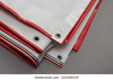 A red and white billboard. PVC fabric folded. Banner with eyelets. Selective focus. - Shutterstock ID 2121585119