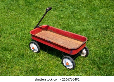 Red White And Black Four Wheeled Child Pull Wagon Outdoors In Grassy Backyard