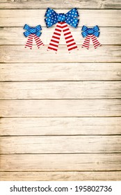 Red White and Blue American Flag Bow Decorations on Rustic Wood Board Background with room or space for copy, text.  Vintage Sepia vertical