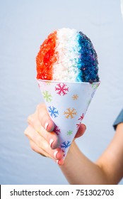 Red, White And Blue Snow Cone In Paper Cone And Blue Straw Held By Female Hands.