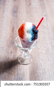 Red, White And Blue Snow Cone In Paper Cone And Blue Straw Held By Female Hands.