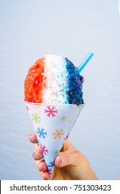 Red, White And Blue Snow Cone In Paper Cone And Blue Straw Held By Female Hands.