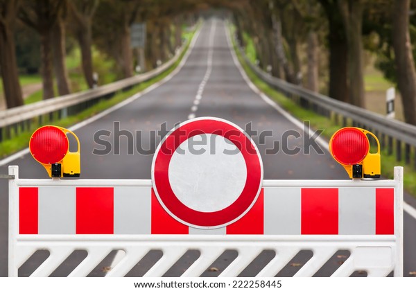 Red and white colored street barrier at an empty\
road/Closed Road