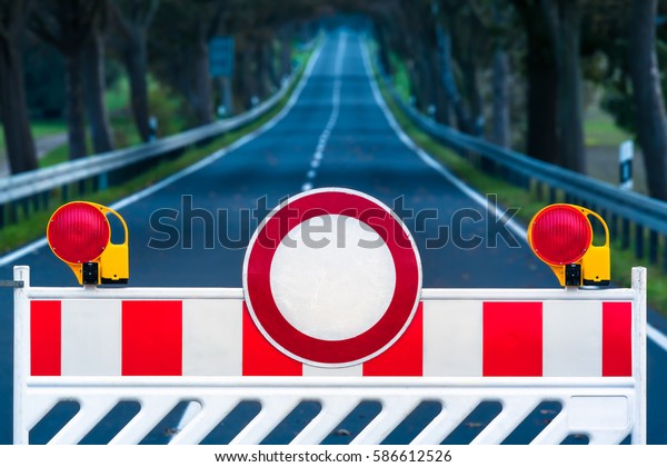 Red and white colored street barrier on empty\
road at night/Closed Road at\
Darkness