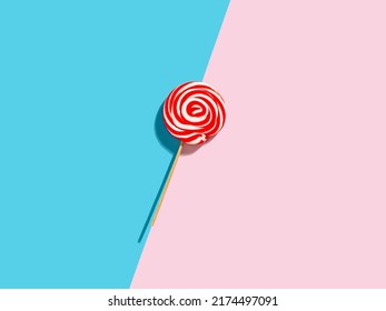 Red And White Colored Swirl Round Candy Lollipop On Pink And Blue Duotone Background.