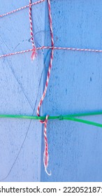 Red And White Cord And Green Plastic Bridle Tied In Blue Stucco Pillar