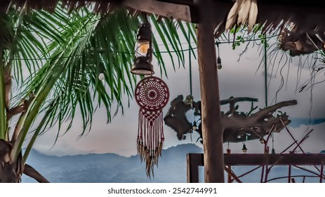 A red and white dreamcatcher hangs from a tree. The dreamcatcher is hanging from a wooden pole - Powered by Shutterstock