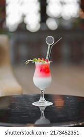 Red And White Drink, With Red Fruit Garnish. Set On A Dark And Shiny Table.