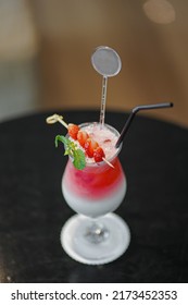 Red And White Drink, With Red Fruit Garnish. Set On A Dark And Shiny Table.