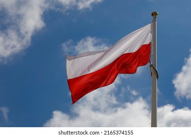 The red and white flag of Poland flutters in the wind on a windy day.