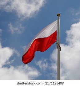 The red and white flag of Poland flutters in the wind on a windy day.
