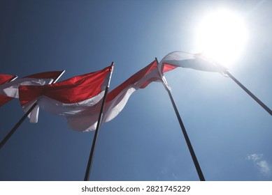 Red And White Flags Waving In Wind Against A Clear Blue Sky On Sunny Day