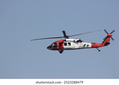 A red and white helicopter flying high in the clear sky, showcasing motion and adventure in the open air - Powered by Shutterstock