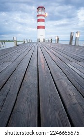 Red and white lighthouse on a cloudy morning with wooden jetty leading to it, vertical, Austria - Shutterstock ID 2246655675