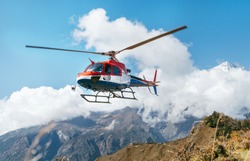 Red And White Medical Rescue Helicopter Landing In High Altitude Himalayas Mountains. Safety And Travel Insurance Concept Image.