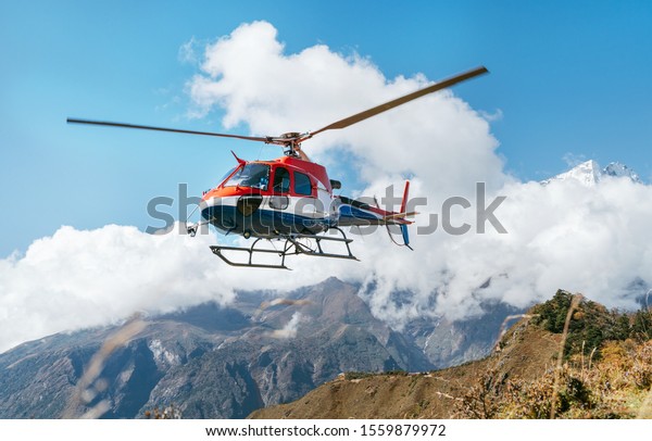Red and white Medical Rescue helicopter landing in\
high altitude Himalayas mountains. Safety and travel insurance\
concept image.