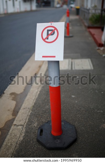 red and white, parking sign on a post in a street side\
walk 