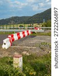 Red and white plastic barrier blocking a road with hills and a milestone
