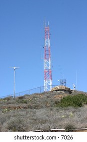 red and white radio tower atop a hill