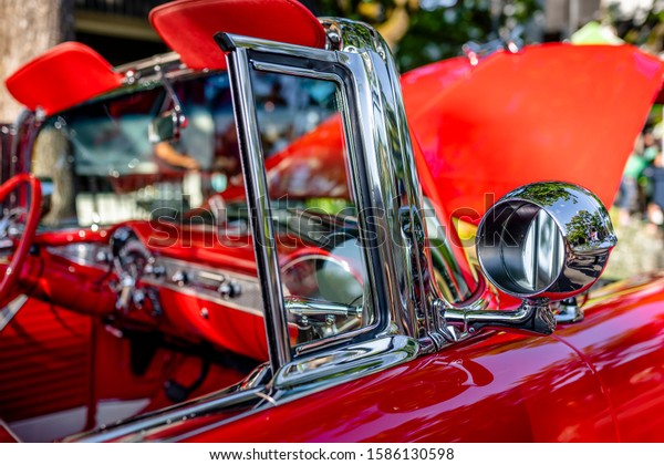 Red and white rarity executive vintage retro\
convertible car with open top and red leather trim and seats\
exhibited at traditional indoor exhibition of old cars in a small\
American provincial town