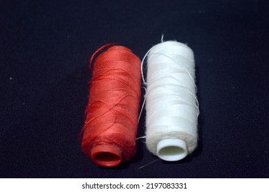 Red And White Sewing Thread On A Black Background