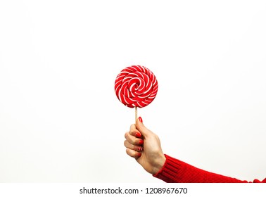 Red and white spiral lollipop in woman hand isolated on white background. Girls holding hard candy cane caramel on stick, sweets holidays concept, copy space for text