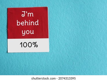 Red And White Sticker On Blue Copy Space Background Written - I Am Behind You 100% - Means Totally Support Someone, Telling Them You Completely Behind Them, Encouragement Note