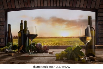 Red Or White. Still Life With Wine Glasses, Bottles, Grapes On Table In Wine Cellar. Panoramic Window View Of Vineyards At Sunset. Tasting, Festivals, Sophisticated Lifestyle And Winemaking Concept