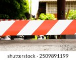 A red and white striped barrier is on a wall. The barrier is on the side of a road