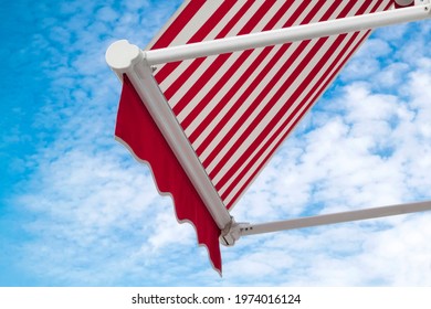 Red And White Striped Cafe Canopy Awning Against Blue Cloudy Sky